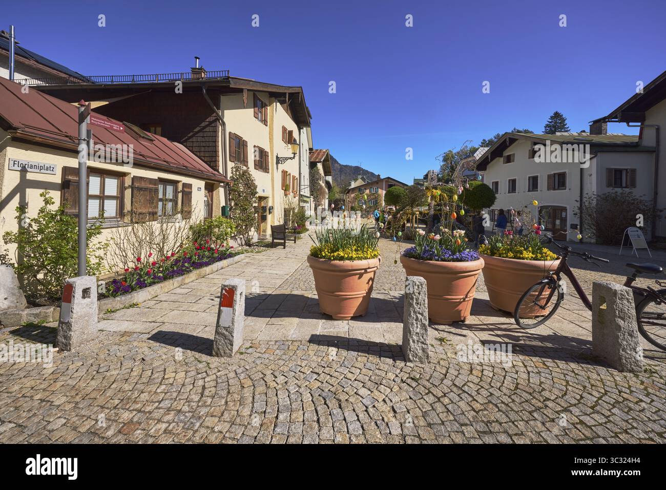 Quadrati, pietre per pavimentazione, lastre di arenaria, case storiche, vasi di fiori, dissuasori, pietre per pavimentazione, lastre di arenaria, cielo blu, senza nuvole, Florianiplatz, Ba Foto Stock