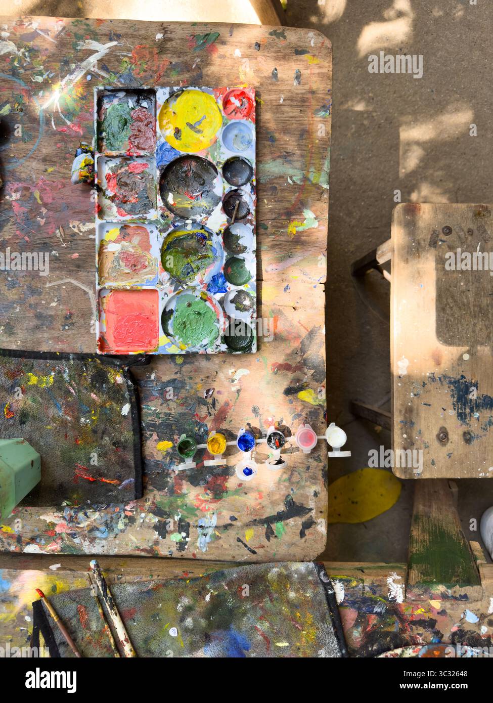 Una vivace tavolozza di artisti con colori colorati spruzza su un tavolo di legno, che mette in mostra creatività ed espressione artistica. Foto Stock