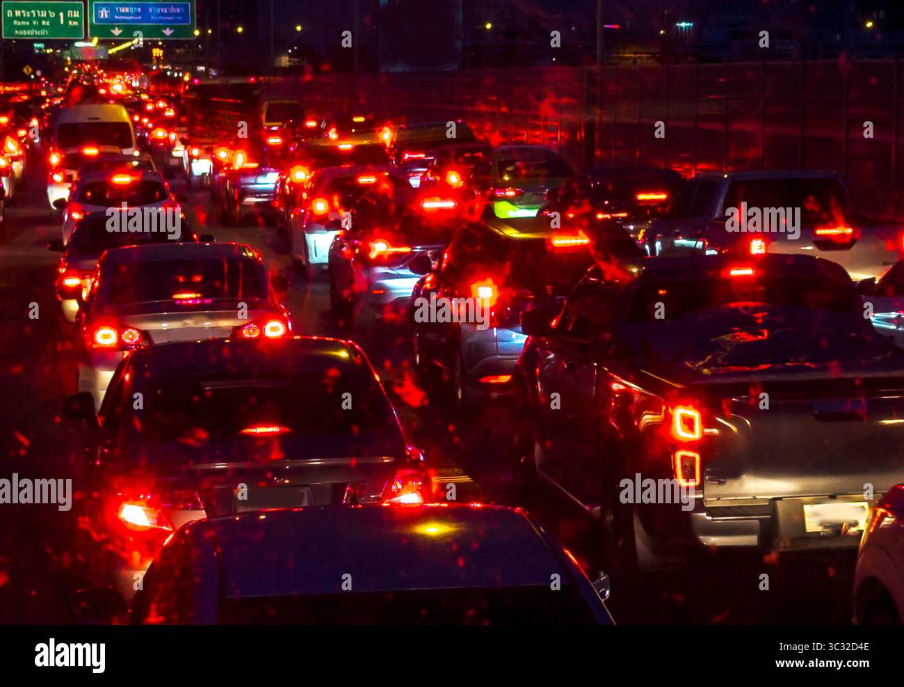 Lunghe file di auto e altri veicoli si accodano, muovendosi lentamente, mentre molte luci rosse brillanti brillano nell'oscurità della notte, su una strada principale trafficata. Foto Stock