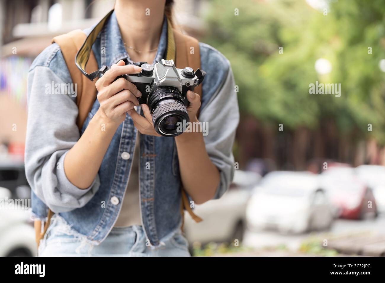 Giovane donna che tiene la macchina fotografica, pronta a immortalare i momenti in città Foto Stock