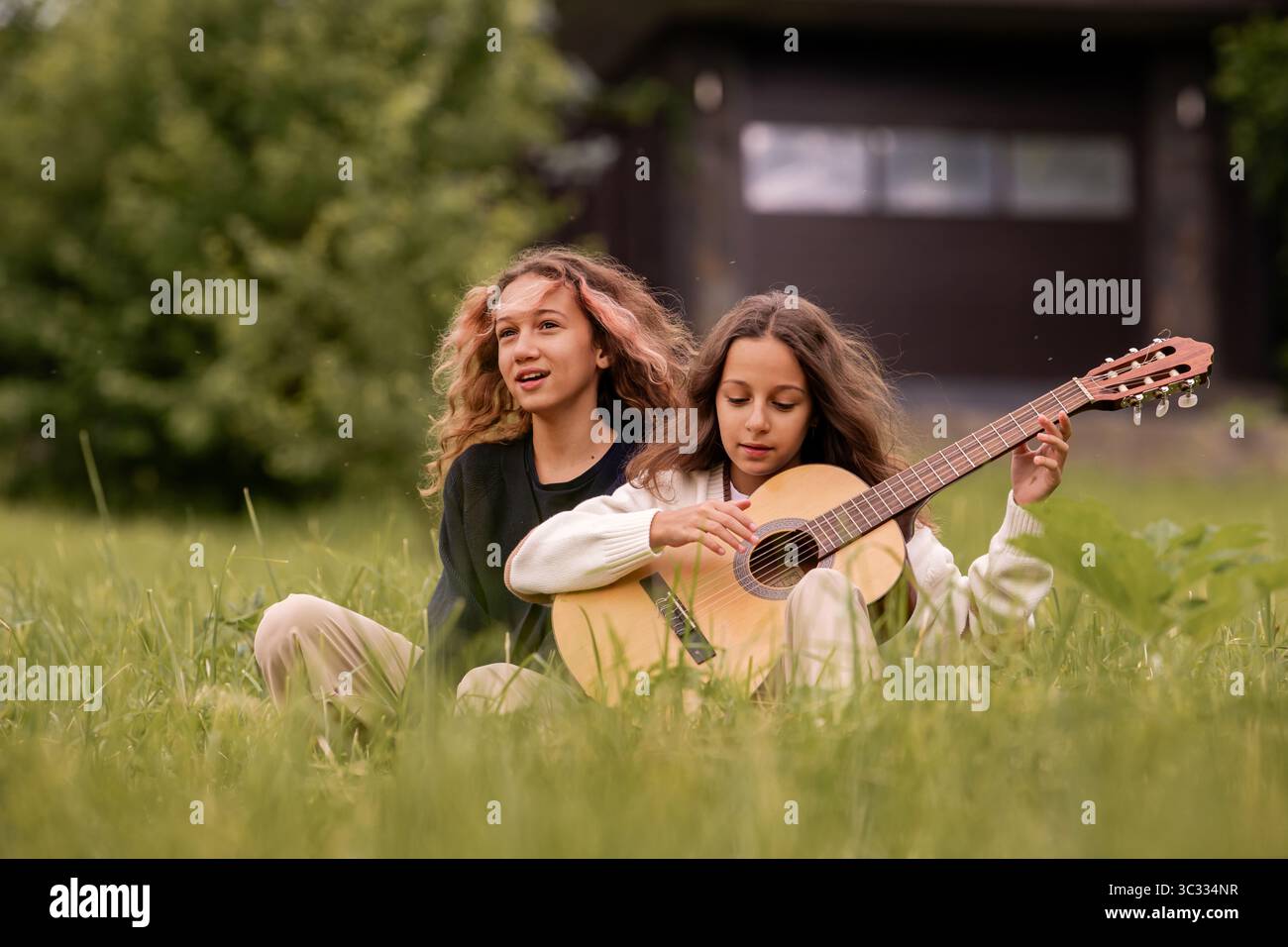 Ragazze gemelle che suonano la chitarra in natura. Foto Stock
