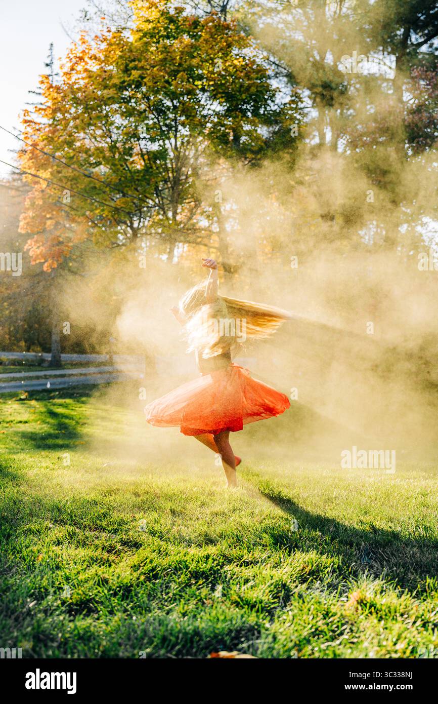La ragazza gira a piedi nudi di polvere dorata sul prato soleggiato Foto Stock
