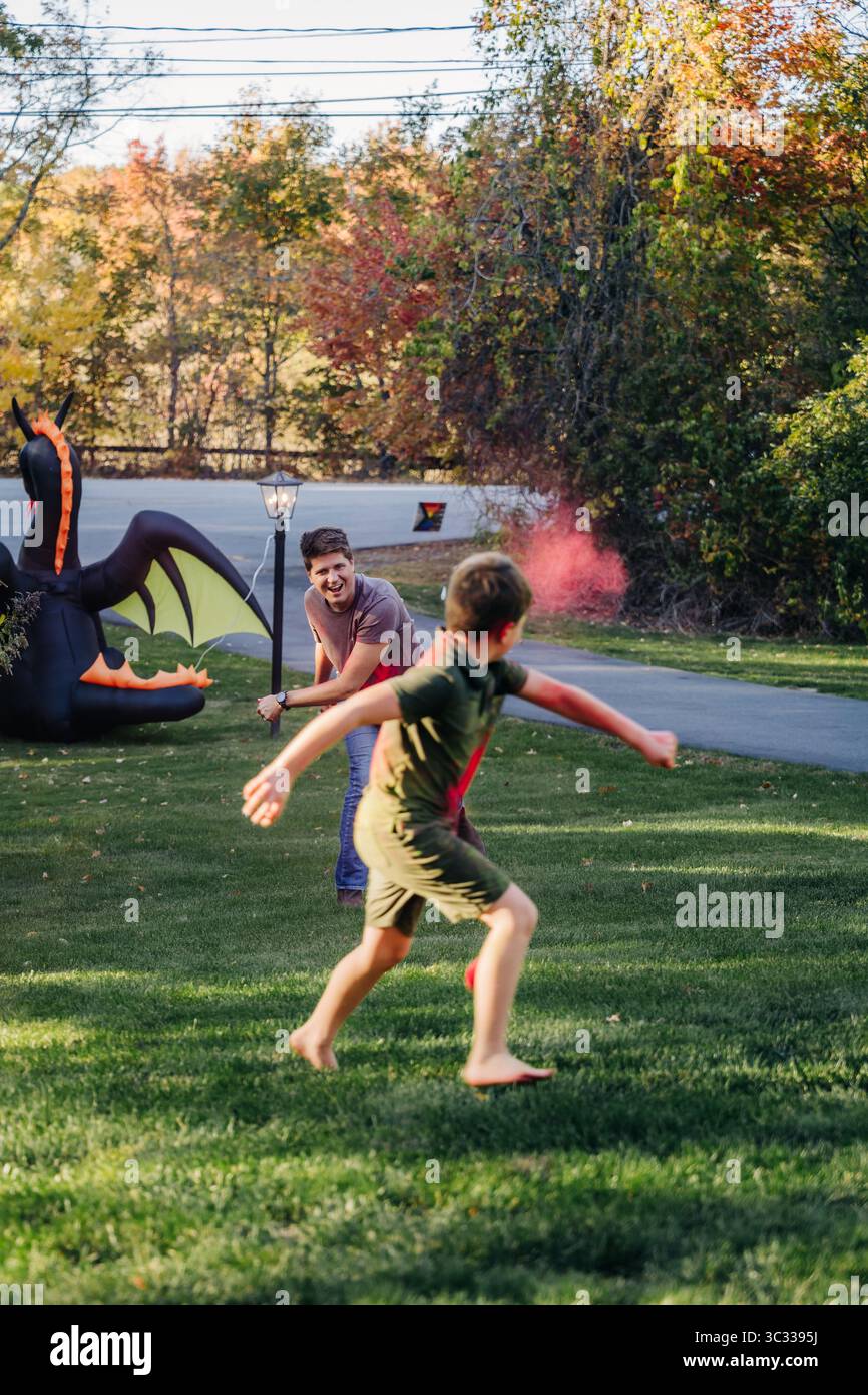 Uomo e bambino giocano con la polvere colorata vicino al drago gonfiabile all'esterno Foto Stock
