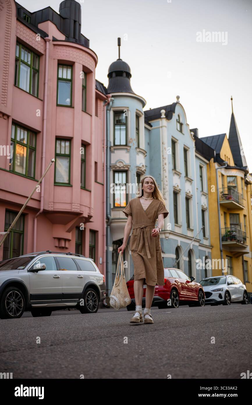 Donna che cammina lungo la via Huvilakatu con edifici colorati a Helsinki Foto Stock