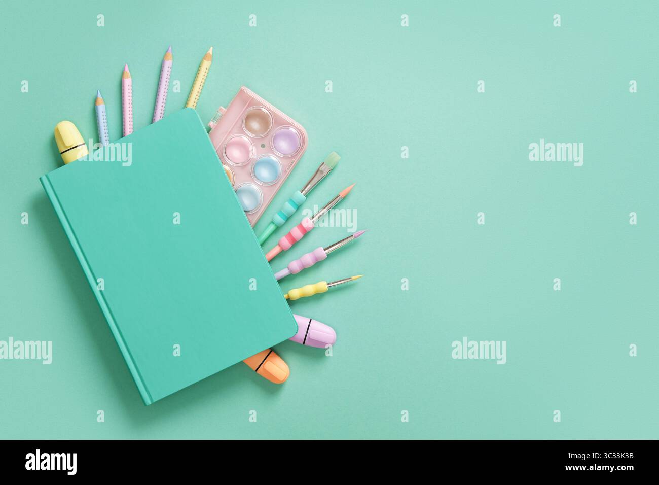 Composizione di varie cartolerie scolastiche e per ufficio in colori pastello verde menta e viola su sfondo blu. Un posto per il testo. Foto Stock