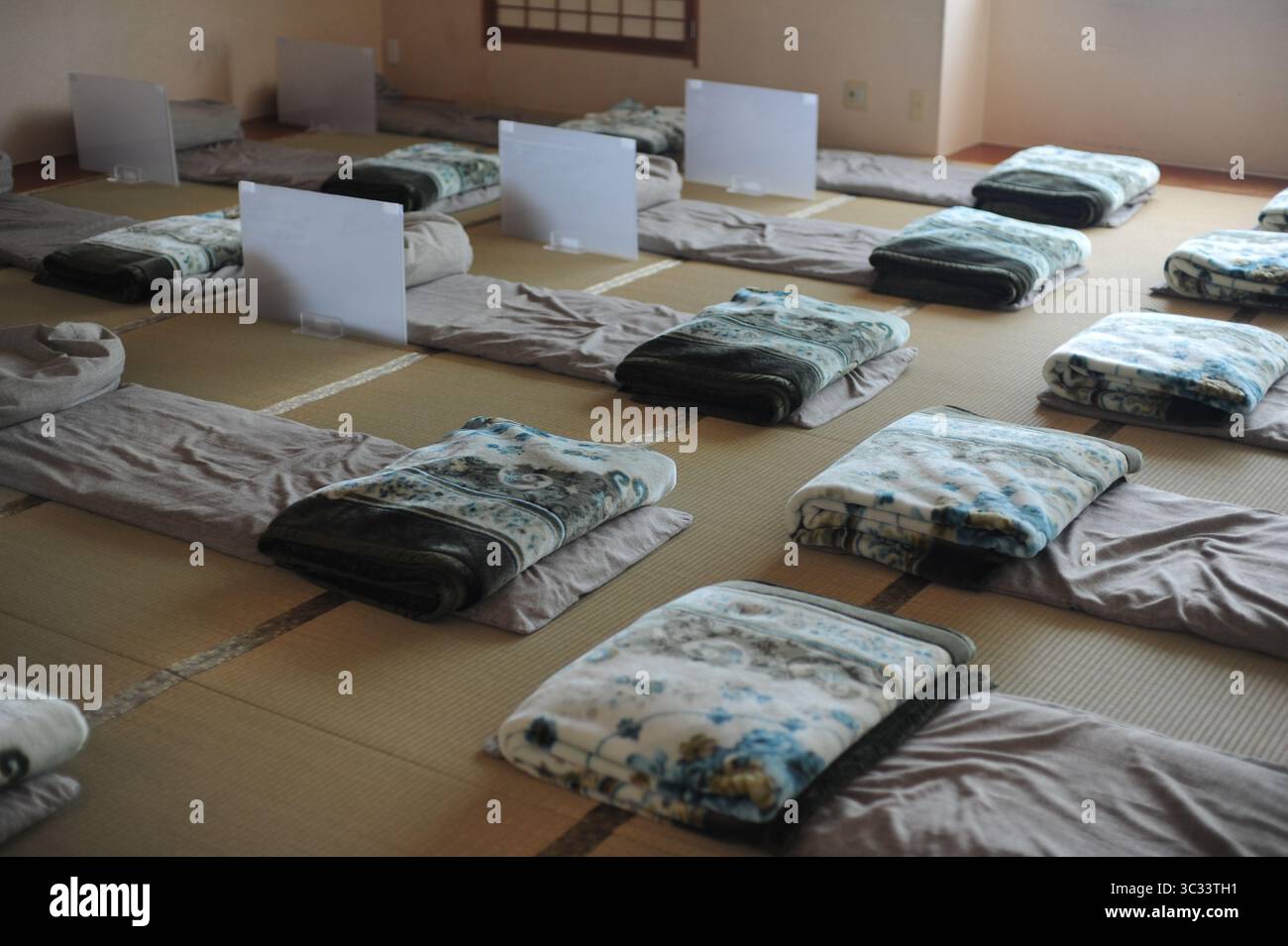Interno di una tradizionale camera d'hotel in Giappone con materassi e cuscini futon e cuscini e tappeti tatami su un pavimento Foto Stock