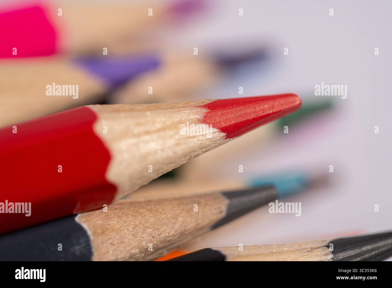 Un primo piano di un mucchio di matite con una rossa, una nera e una blu. Le matite sono di colori e dimensioni diversi Foto Stock