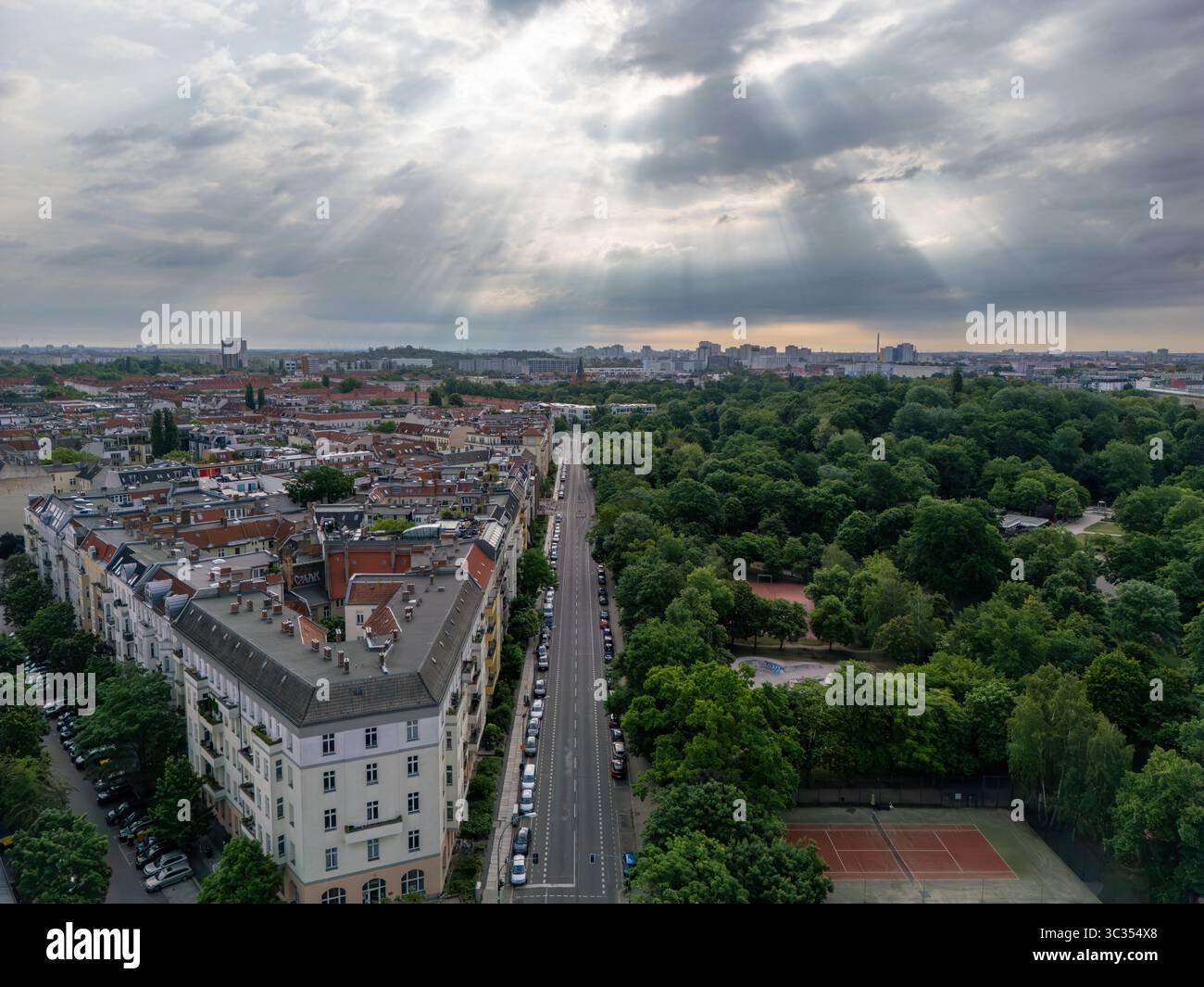 La vista aerea dei raggi del sole attraversa le nuvole sul paesaggio urbano e il lussureggiante parco, dipingendo un netto contrasto tra la natura e la città, Berlino, V. Foto Stock
