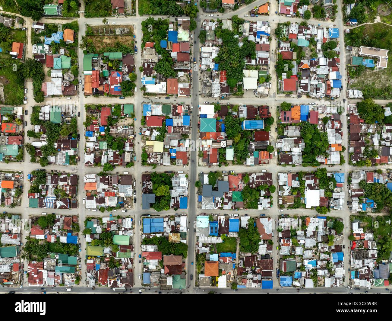 Vista aerea di un vivace arazzo di tetti colorati e lussureggiante vegetazione intersecata da strade simili a una griglia, Siargao Island, Caraga, Filippine. Foto Stock