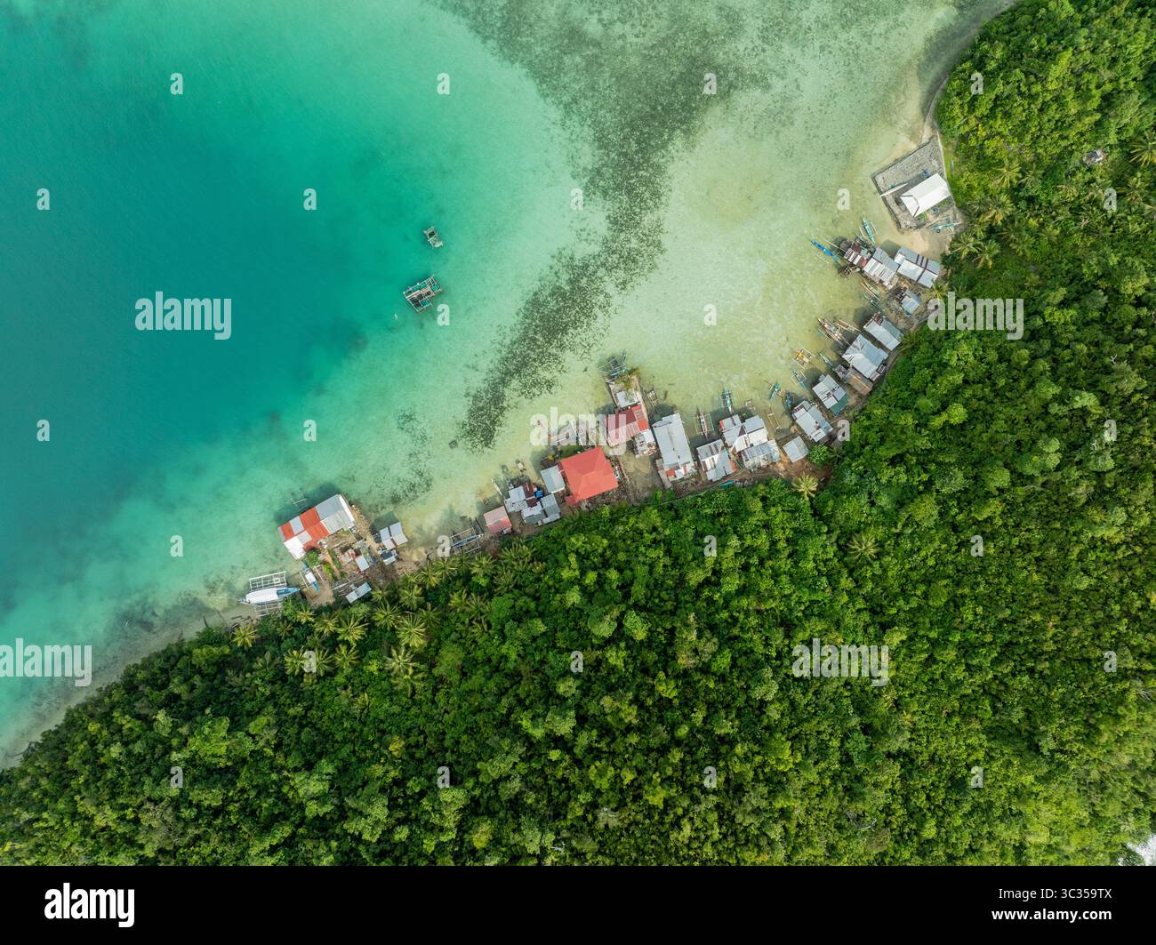 Vista aerea delle case annidate tra la lussureggiante foresta pluviale e le acque turchesi di Siargao Island, Siargao Island, Caraga, Filippine. Foto Stock