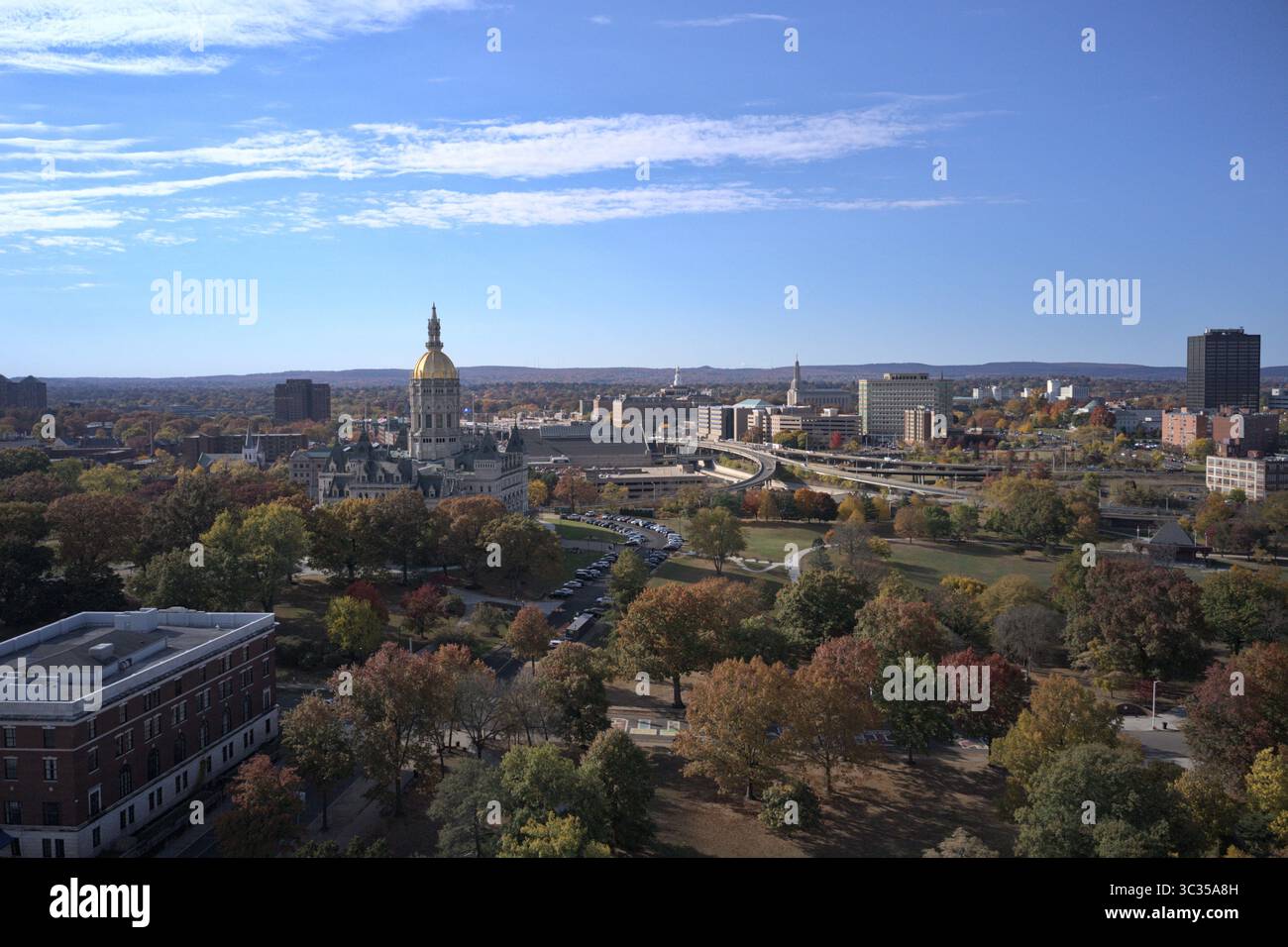 Hartford, Stati Uniti - 4 ottobre 2024: Veduta aerea della cupola del Campidoglio dello Stato del Connecticut che splende sotto un cielo azzurro, incorniciata dal fogliame autunnale e dallo skyline della città. Foto Stock