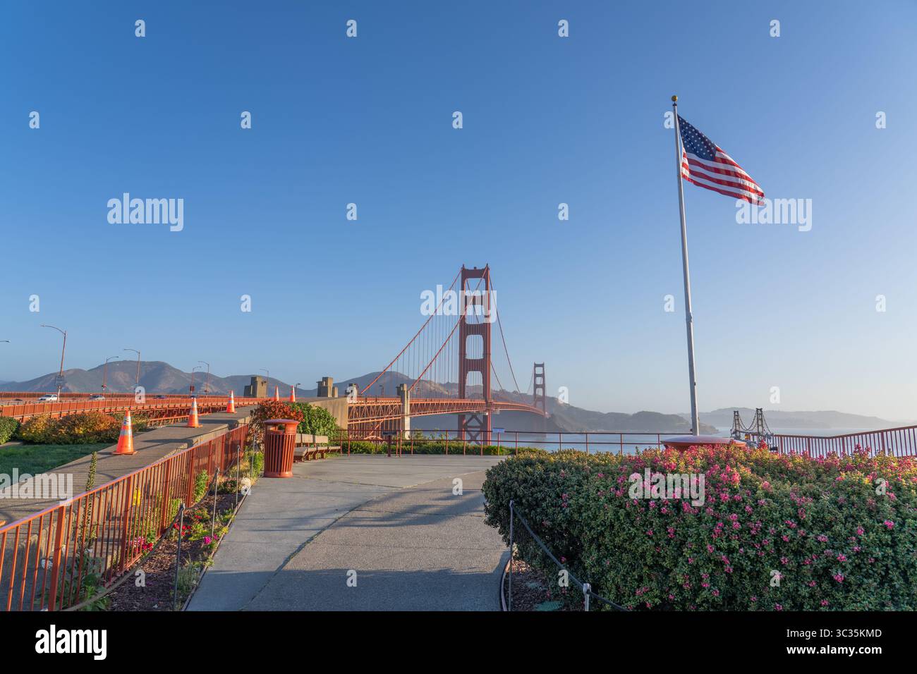 Golden Gate Vista Point, all'alba, con luce soffusa del mattino, cielo blu, bandiera americana al vento. San Francisco, Stati Uniti Foto Stock