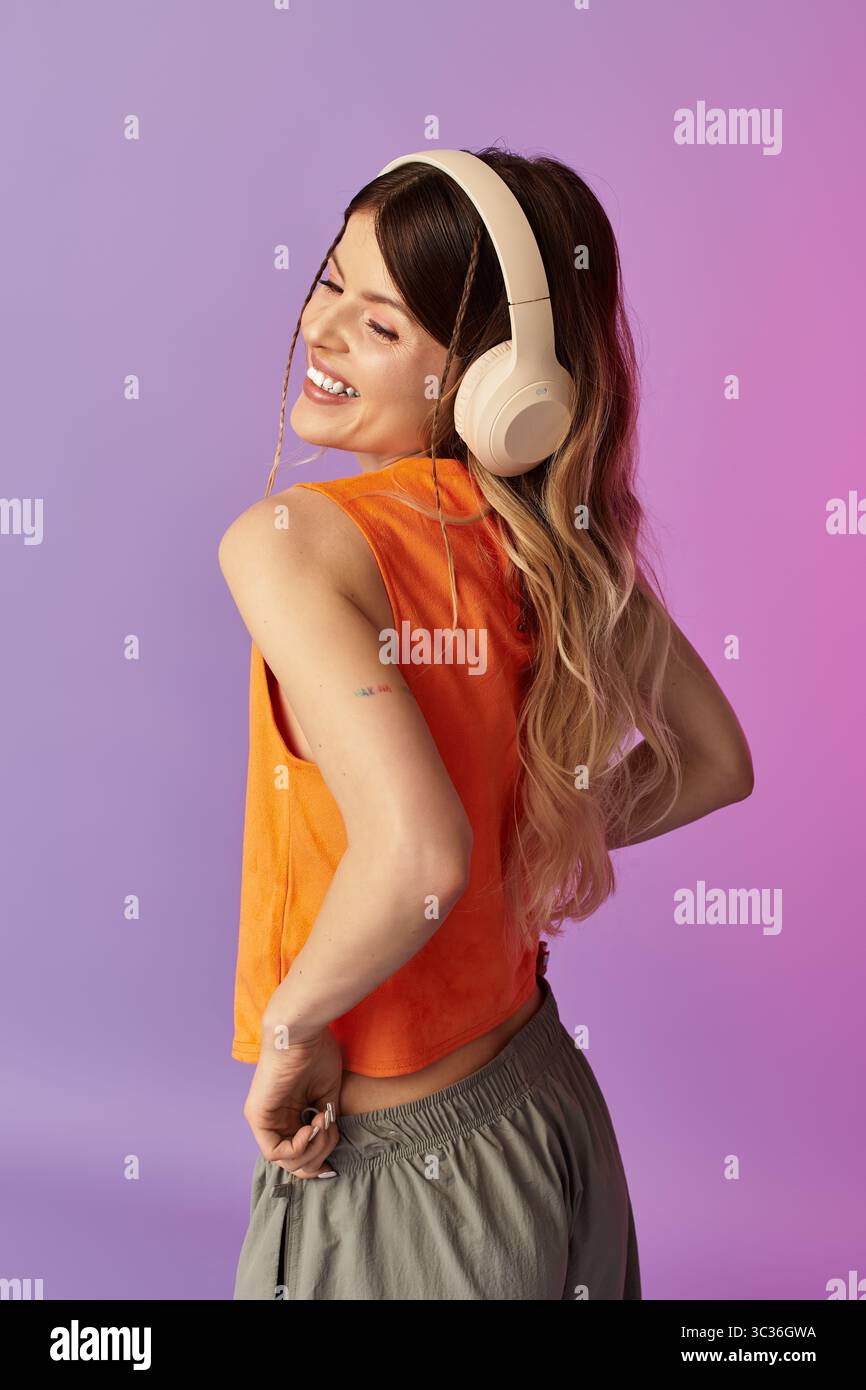 Una giovane donna ama la musica mentre abbraccia un'atmosfera estiva spensierata su uno sfondo colorato Foto Stock
