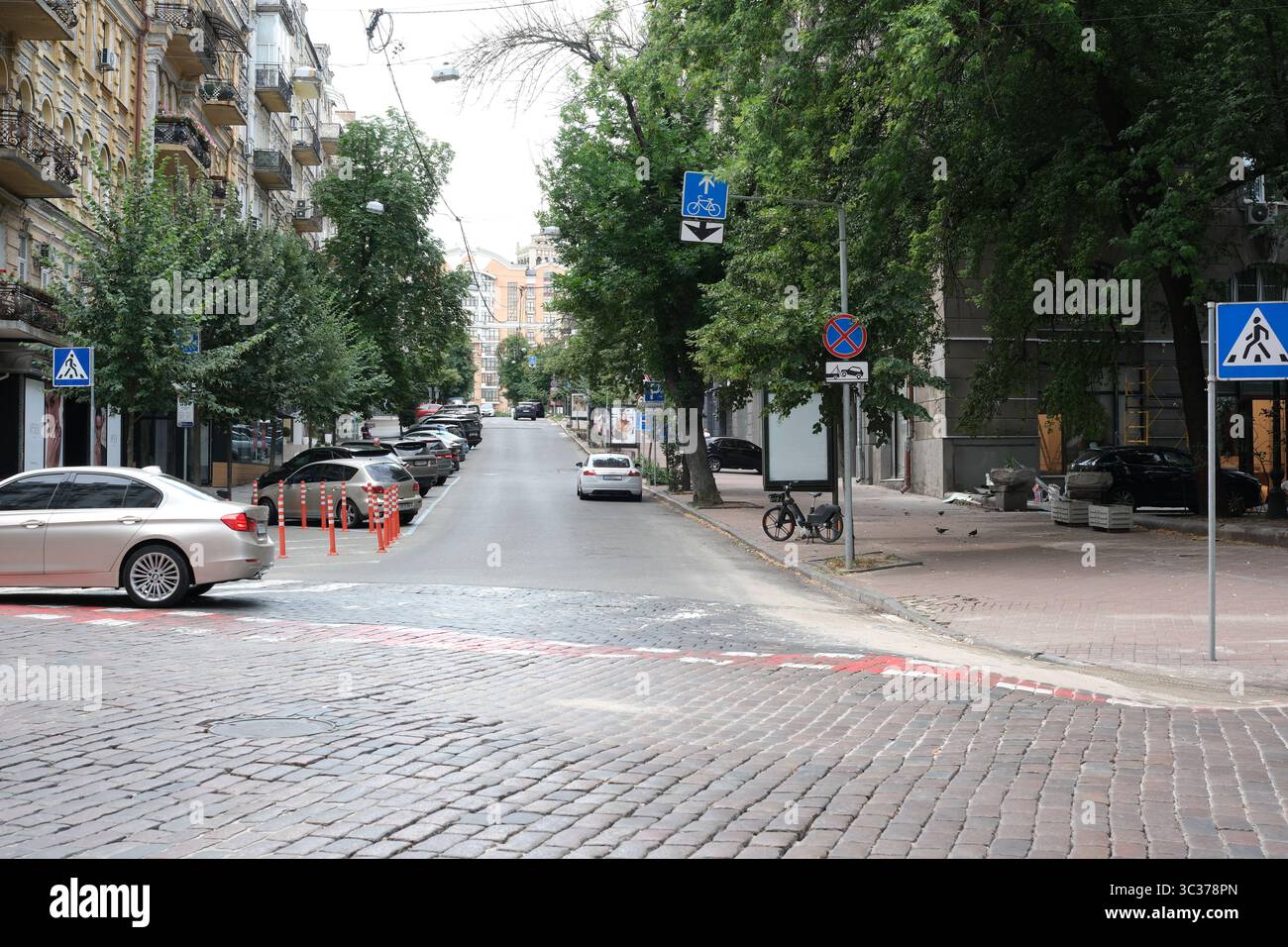 Le strade trafficate di Kiev mostrano auto, ciclisti e lussureggiante vegetazione in una giornata in città. Foto Stock