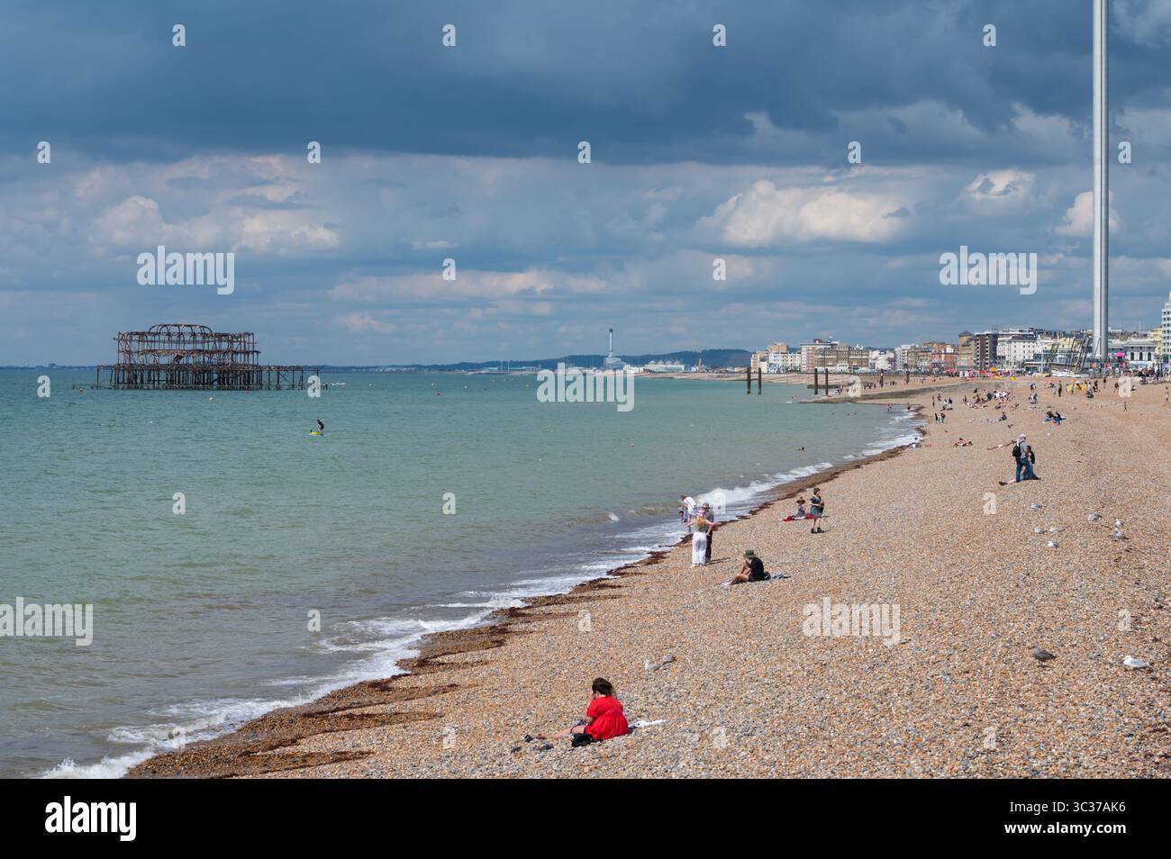 Vista a ovest lungo la costa che mostra la spiaggia di ciottoli e le rovine arrugginite del West Pier a Brighton, Brighton & Hove, East Sussex, Inghilterra, Regno Unito. Foto Stock