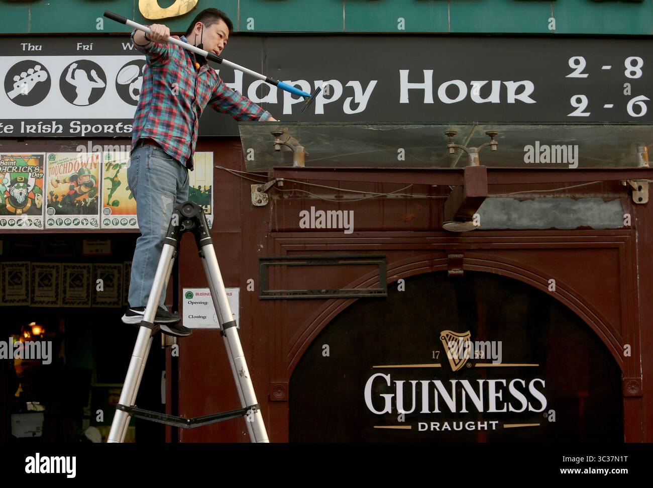 11 aprile 2021, PECHINO, CINA: Un membro del personale cinese indossa una maschera protettiva mentre pulisce l'esterno di un popolare bar occidentale, completamente aperto per gli affari, a Pechino domenica 11 aprile 2021. La capitale cinese ha ridotto l'obbligo di indossare maschere protettive, ad eccezione dei trasporti pubblici, e il distanziamento sociale, mentre la città torna lentamente alla vita pre-covid 19 con ristoranti, aziende e scuole completamente aperti. (Immagine di credito: © Todd Lee/ZUMA Wire) Foto Stock