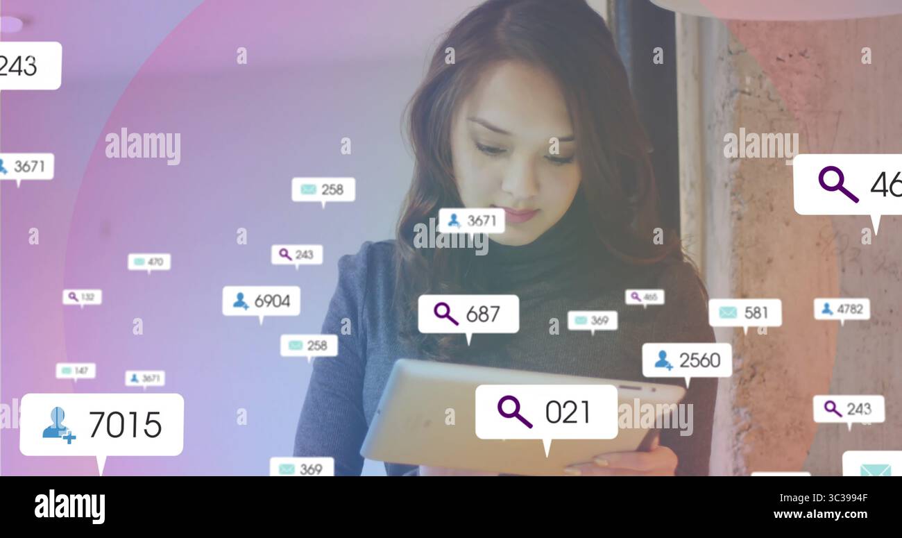 Donna asiatica che tiene un tablet e controlla le icone di notifica fluttuanti in ufficio, con un muro di cemento Foto Stock