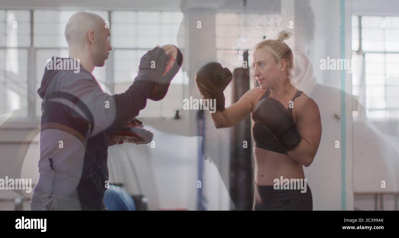 Donna apprendista che indossa guanti da boxe che pungono i guanti a fuoco nell'area fitness della palestra di boxe, spazio fotocopie Foto Stock