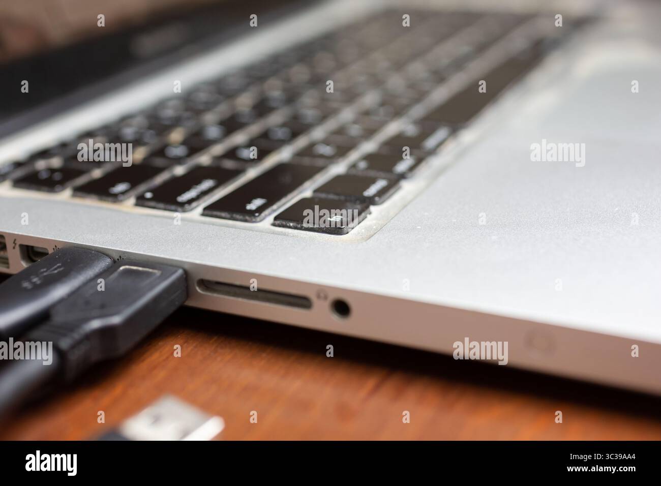 Una vista del pannello laterale e dell'area delle uscite delle porte di un computer portatile su una scrivania di legno. Foto Stock