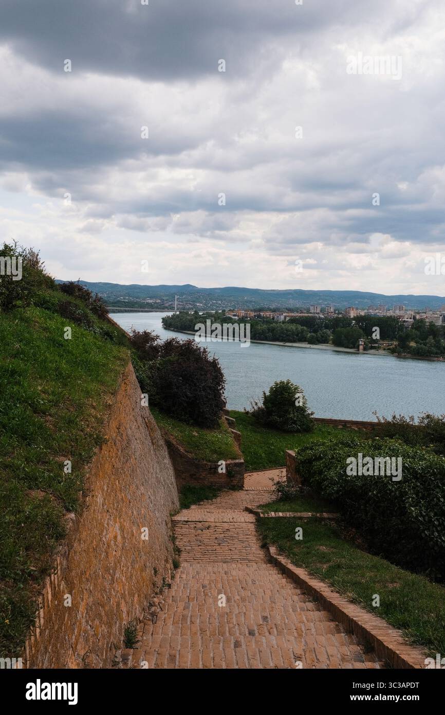 Percorso in mattoni che scende dalla Fortezza di Petrovaradin con vista sul fiume Danubio e sulla città di Novi Sad, in Serbia Foto Stock