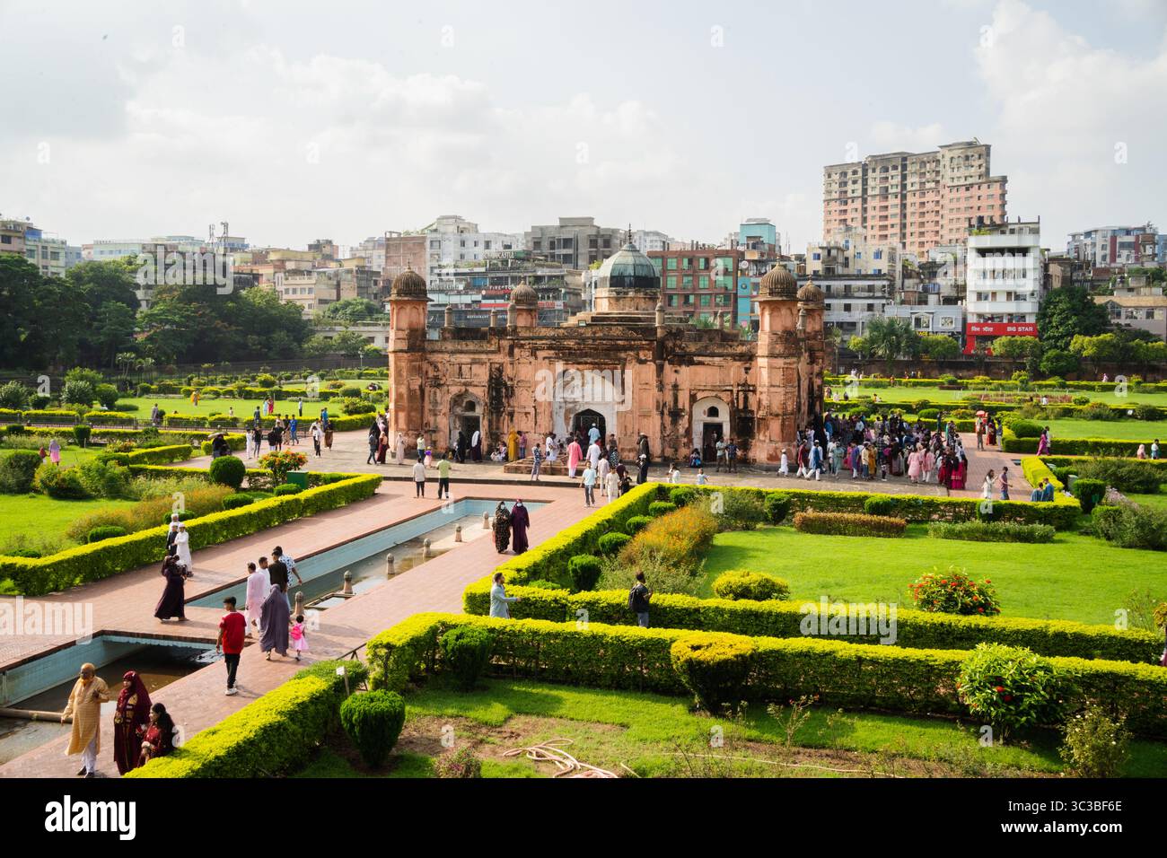 Il forte di Lalbagh a Dacca, Bangladesh, un maestoso edificio di epoca Moghul, sorge tra lussureggianti giardini verdi e piscine riflettenti, con il moderno paesaggio urbano Foto Stock