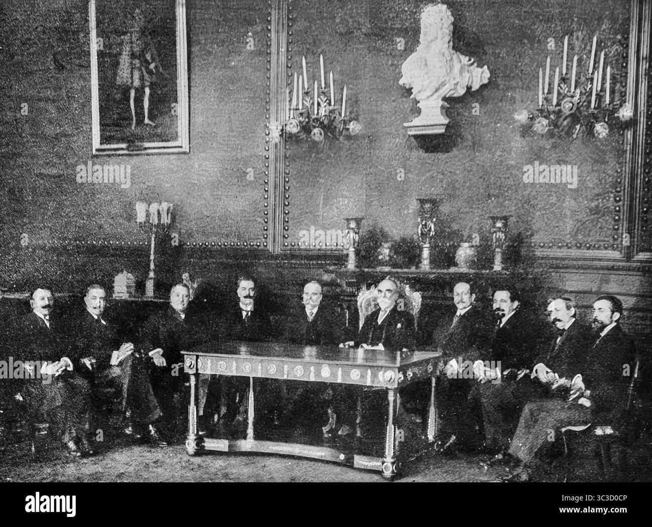 Il nuovo Ministero della difesa portoghese tiene il suo primo consiglio sotto il presidente Bernardino Machado al Palazzo di BelÈm, Lisbona, come pubblicato a LíIllustration, 25 marzo 1916. Questo momento storico ha segnato lo spostamento verso la cooperazione alleata durante la prima guerra mondiale Portugalís ritratto di dieci figure governative chiave sedute sotto un busto e pareti a lume di candela in una sala di stato ornata. Immagine di archivio in bianco e nero. Foto Stock