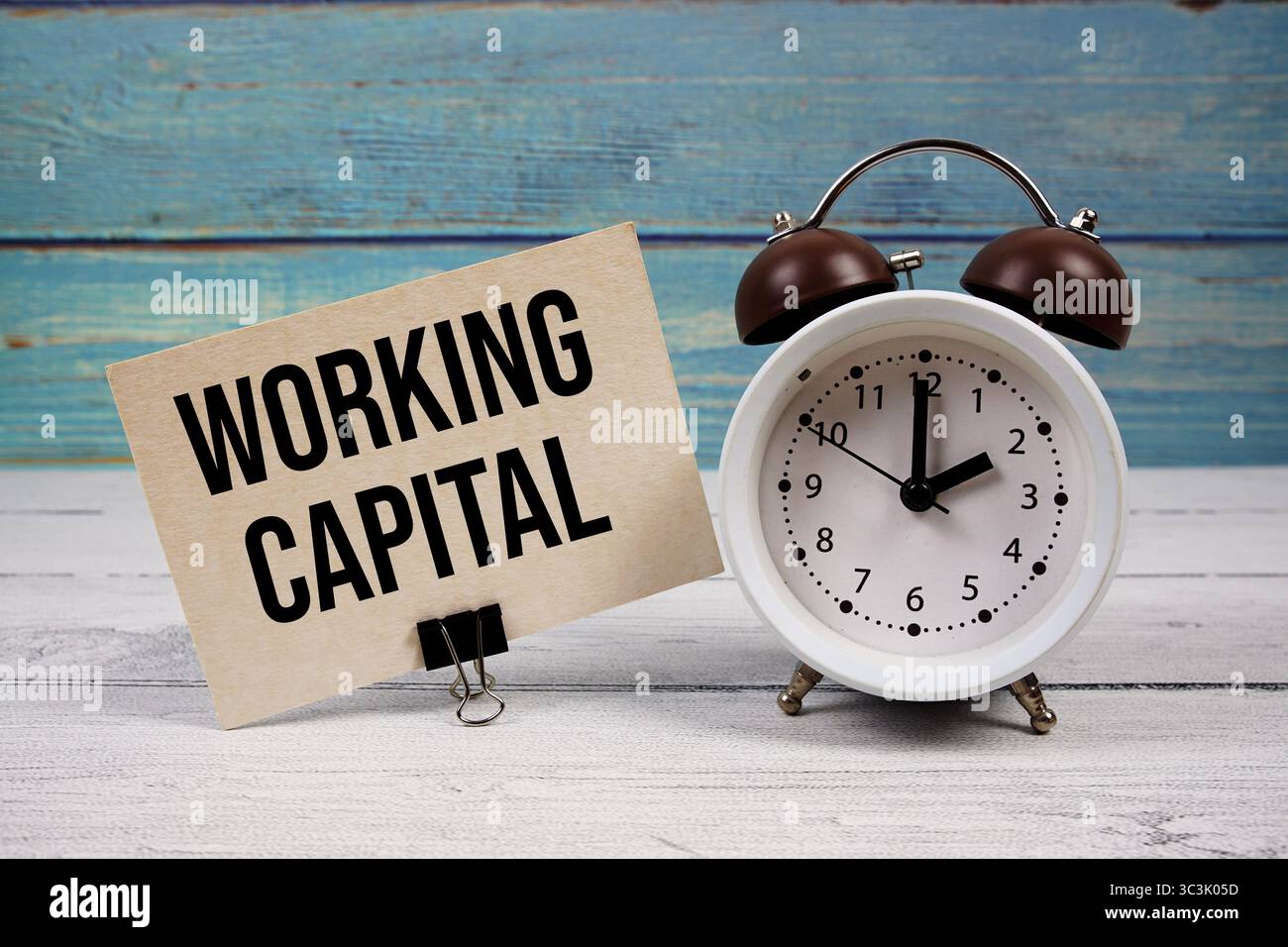 Testo Working Capital scritto su carta con sveglia su sfondo in legno Foto Stock
