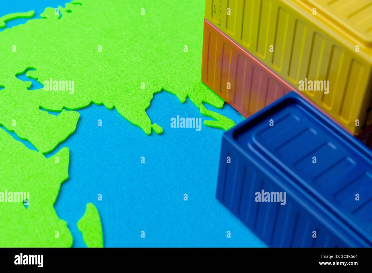 Contenitori di spedizione in miniatura su una mappa dei continenti. Logistica globale, commercio internazionale e il concetto di movimento delle merci in tutto il mondo. Foto Stock