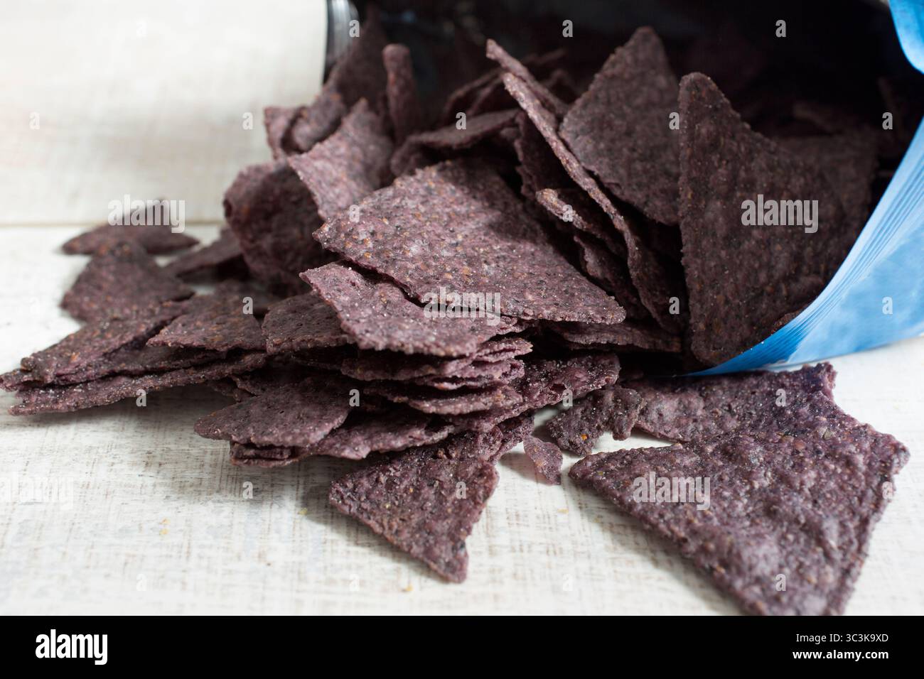 Una vista dei trucioli di tortilla di mais blu che fuoriescono dalla confezione del prodotto. Foto Stock