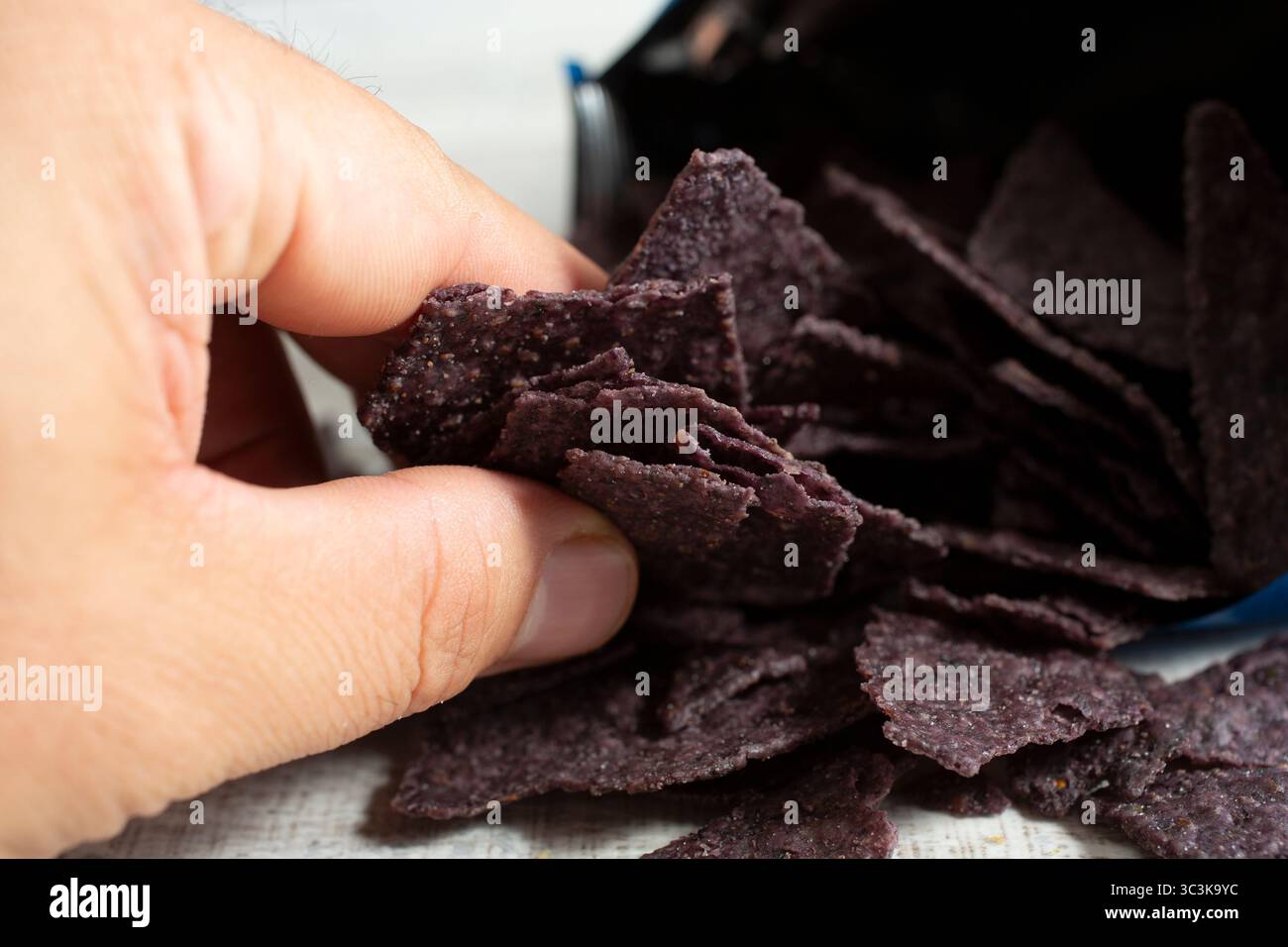 Una vista di una mano che afferra delle tortilla di mais blu. Foto Stock