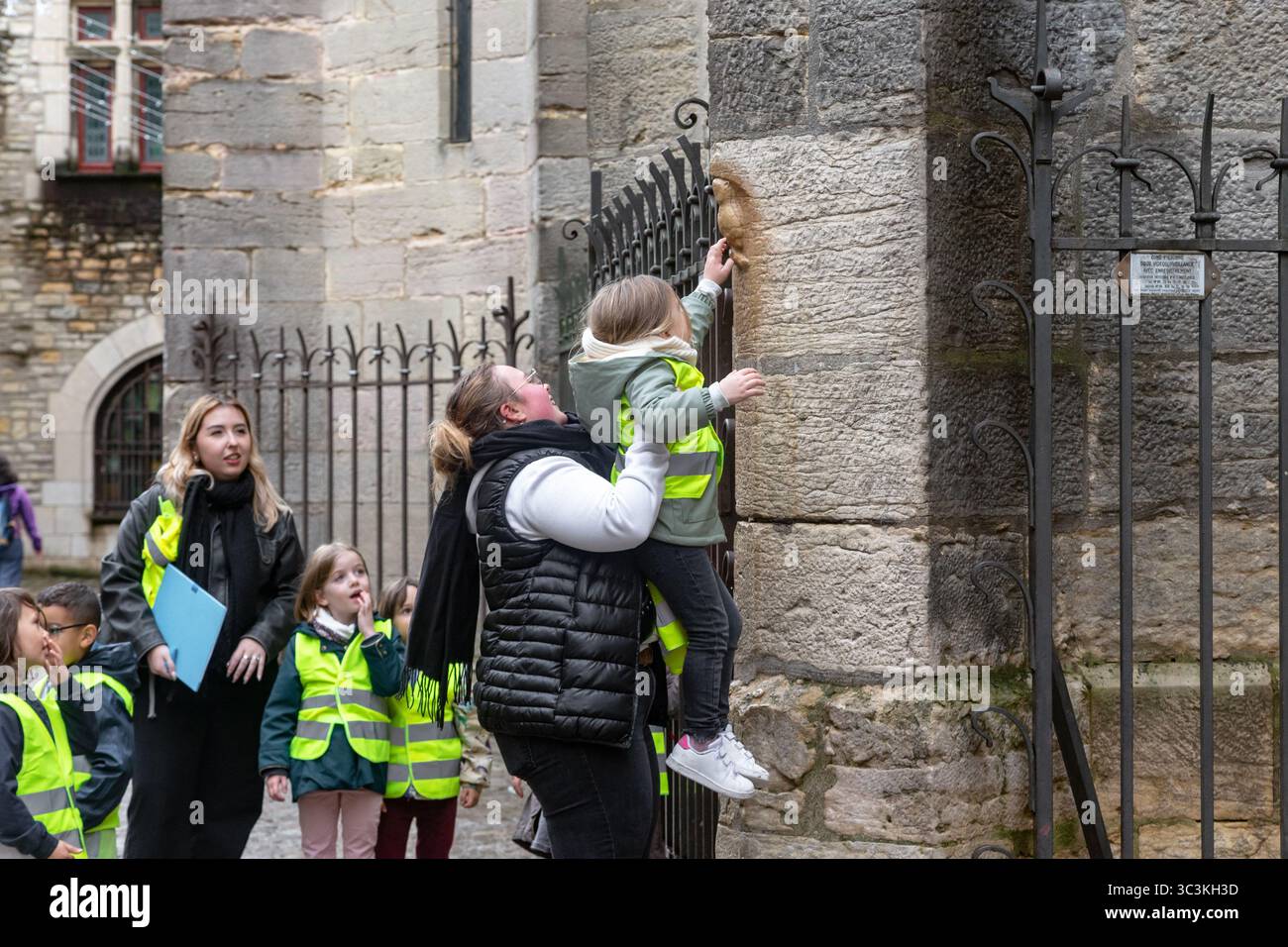 DIGIONE, FRANCIA - 30 OTTOBRE 2023: Bambini e insegnanti non identificati sono impegnati con il tocco tradizionale del simbolo della città - un gufo di pietra su t Foto Stock