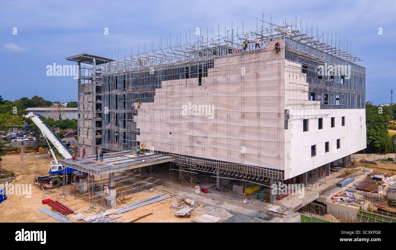 Un edificio a piu' piani in costruzione con struttura in acciaio esposta e ponteggi. Sono in corso lavori di facciata come attrezzatura da costruzione Foto Stock