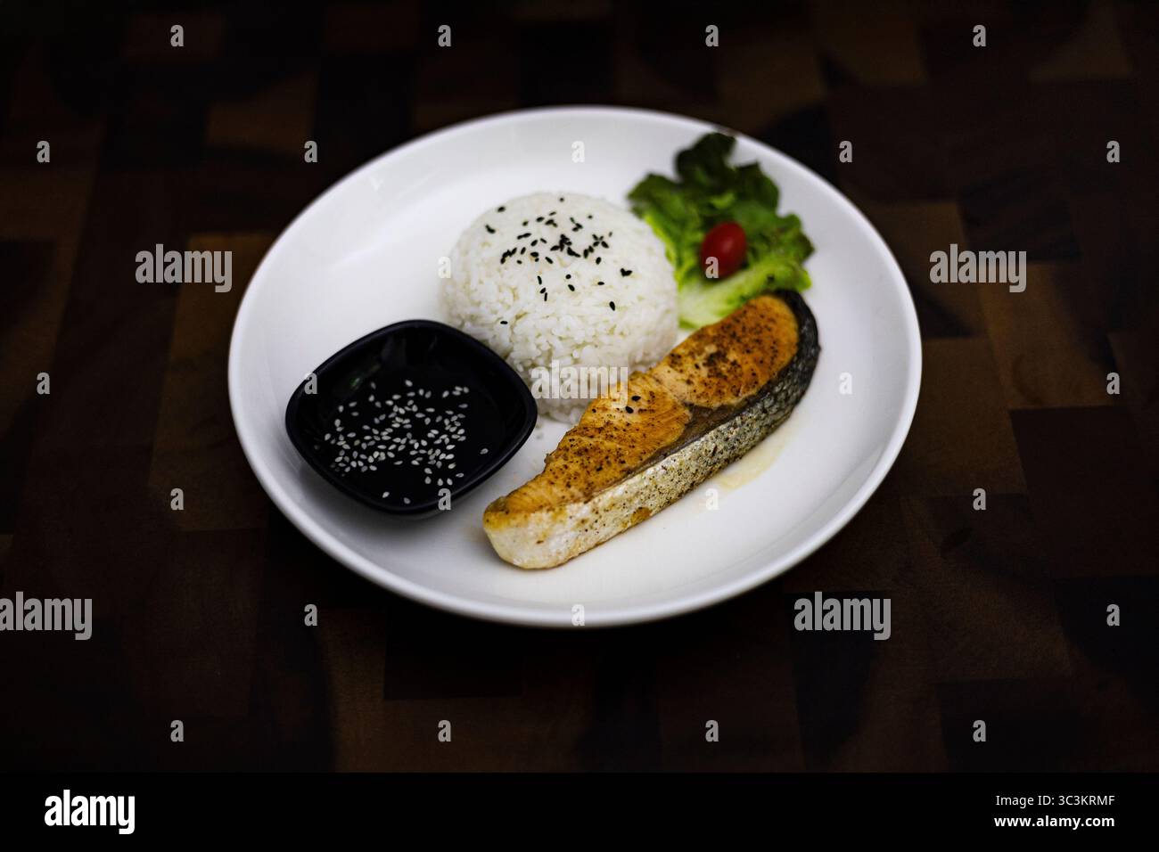 Insalata di salmone grigliata su Un piatto bianco posto su un tavolo di legno, sfondo per la pubblicità e la carta da parati nella scena culturale e gastronomica. Foto Stock