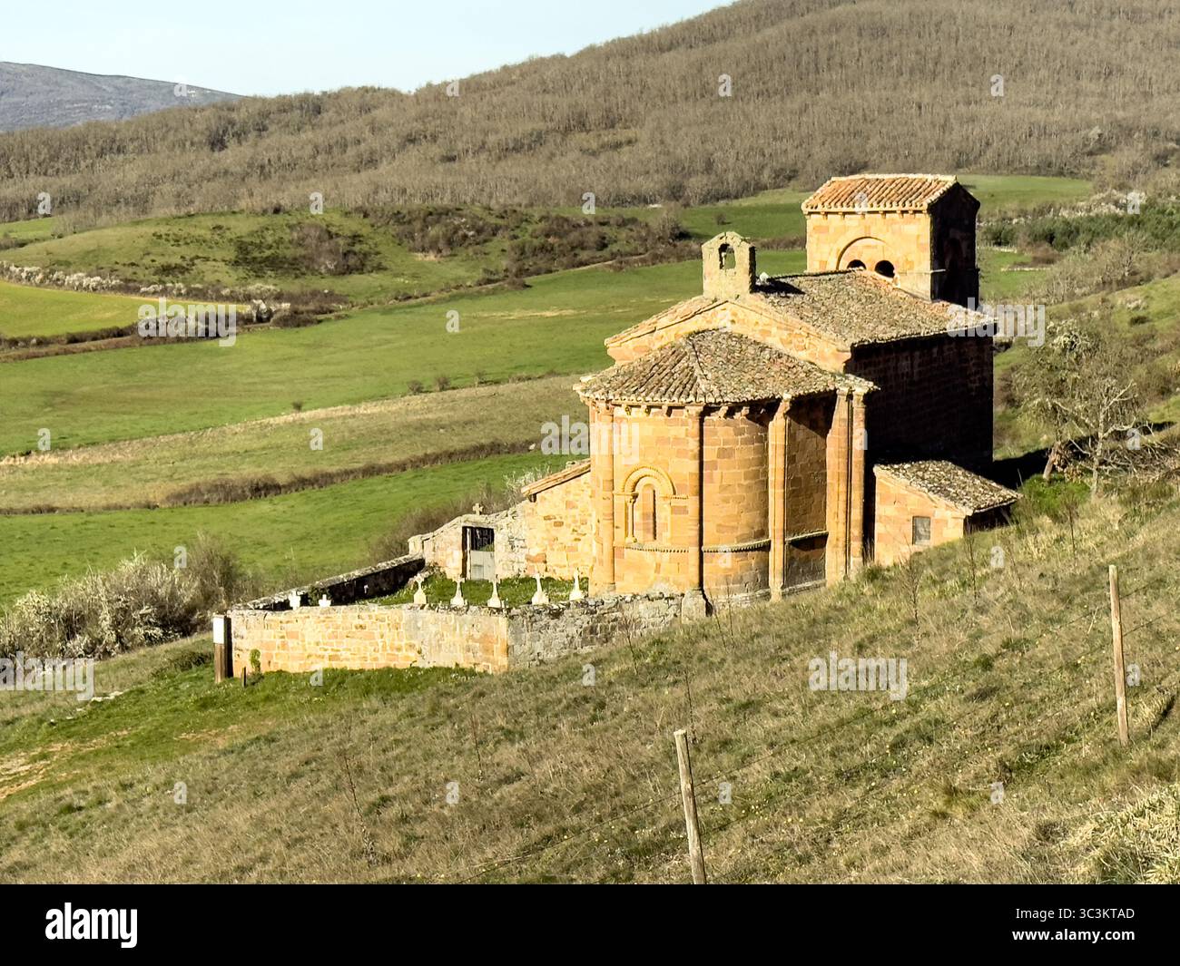 Storica chiesa romanica con pareti in pietra, tetto in piastrelle rosse e campanile annidato nella campagna di Palencia. Foto Stock