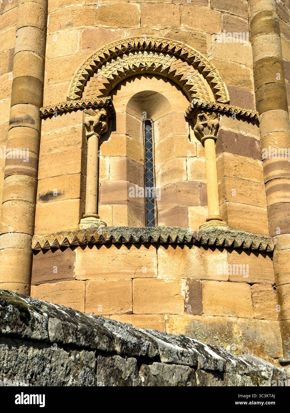 Storica chiesa romanica con pareti in pietra, tetto in piastrelle rosse e campanile annidato nella campagna di Palencia. Foto Stock