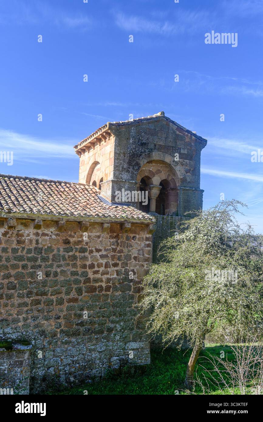 Storica chiesa romanica con pareti in pietra, tetto in piastrelle rosse e campanile annidato nella campagna di Palencia. Foto Stock