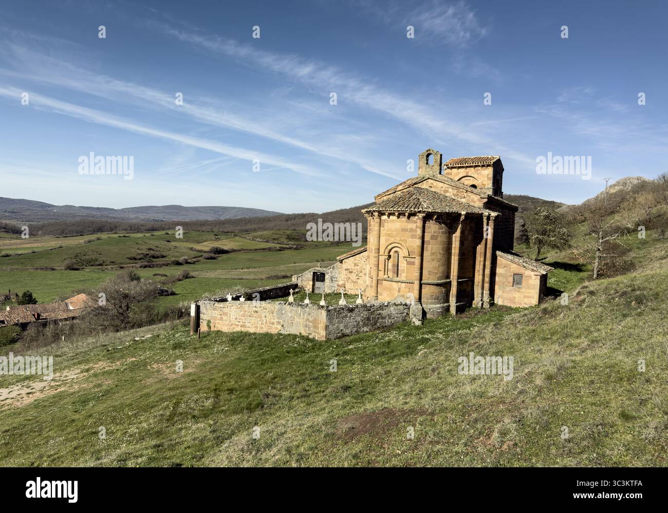 Storica chiesa romanica con pareti in pietra, tetto in piastrelle rosse e campanile annidato nella campagna di Palencia. Foto Stock