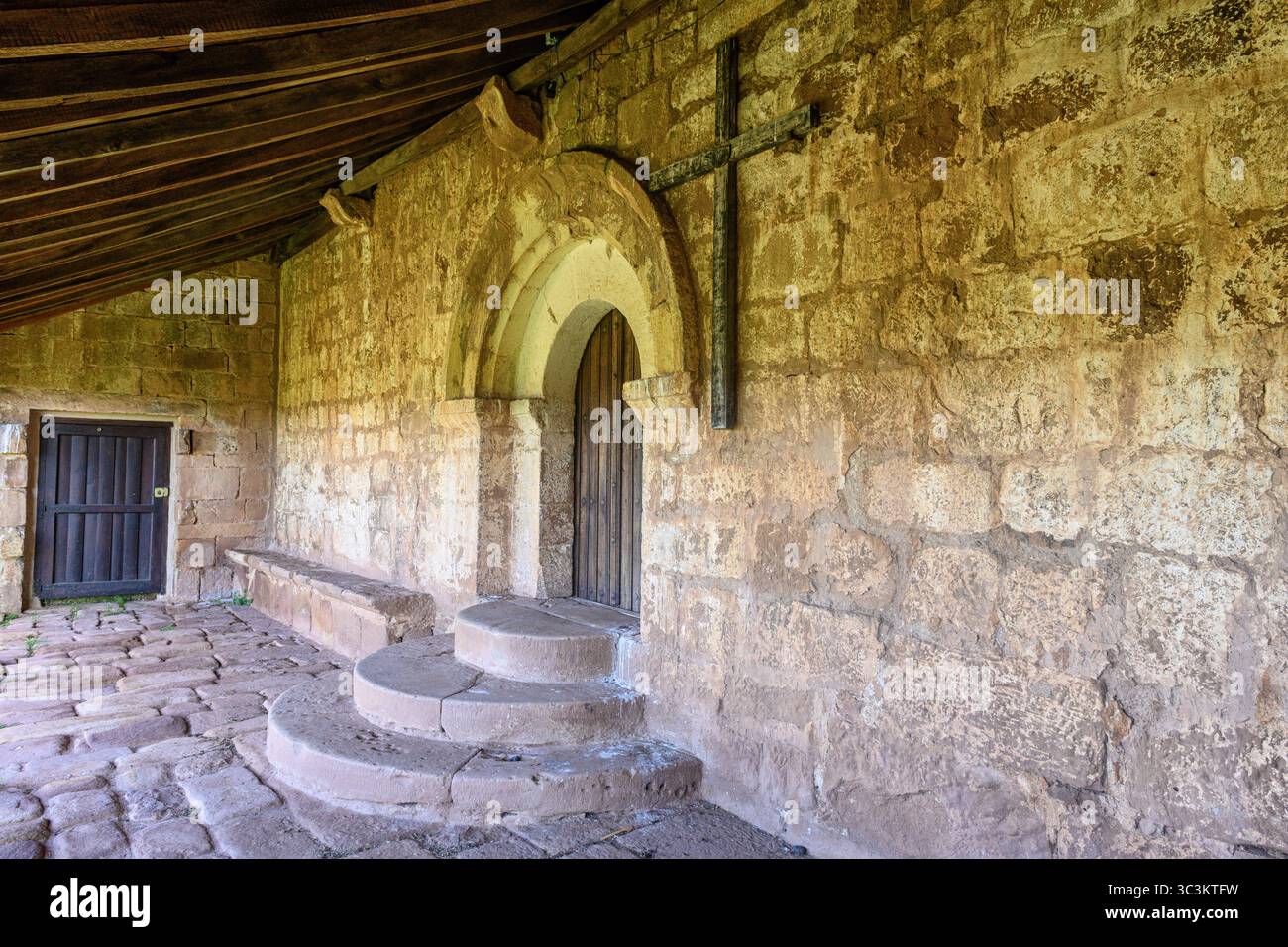 Storica chiesa romanica con pareti in pietra, tetto in piastrelle rosse e campanile annidato nella campagna di Palencia. Foto Stock
