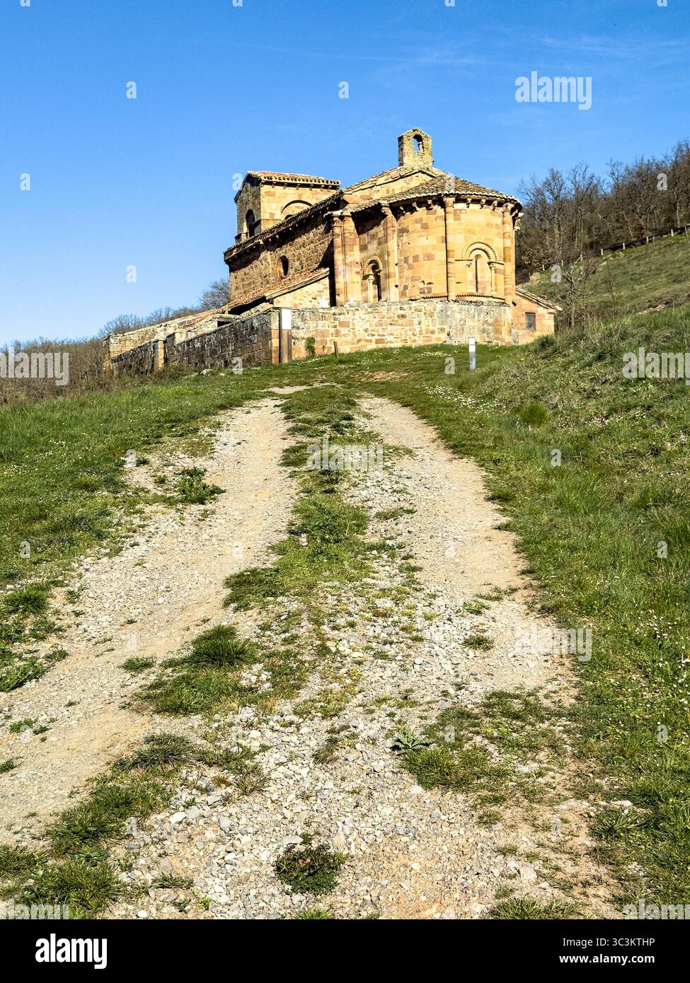 Storica chiesa romanica con pareti in pietra, tetto in piastrelle rosse e campanile annidato nella campagna di Palencia. Foto Stock