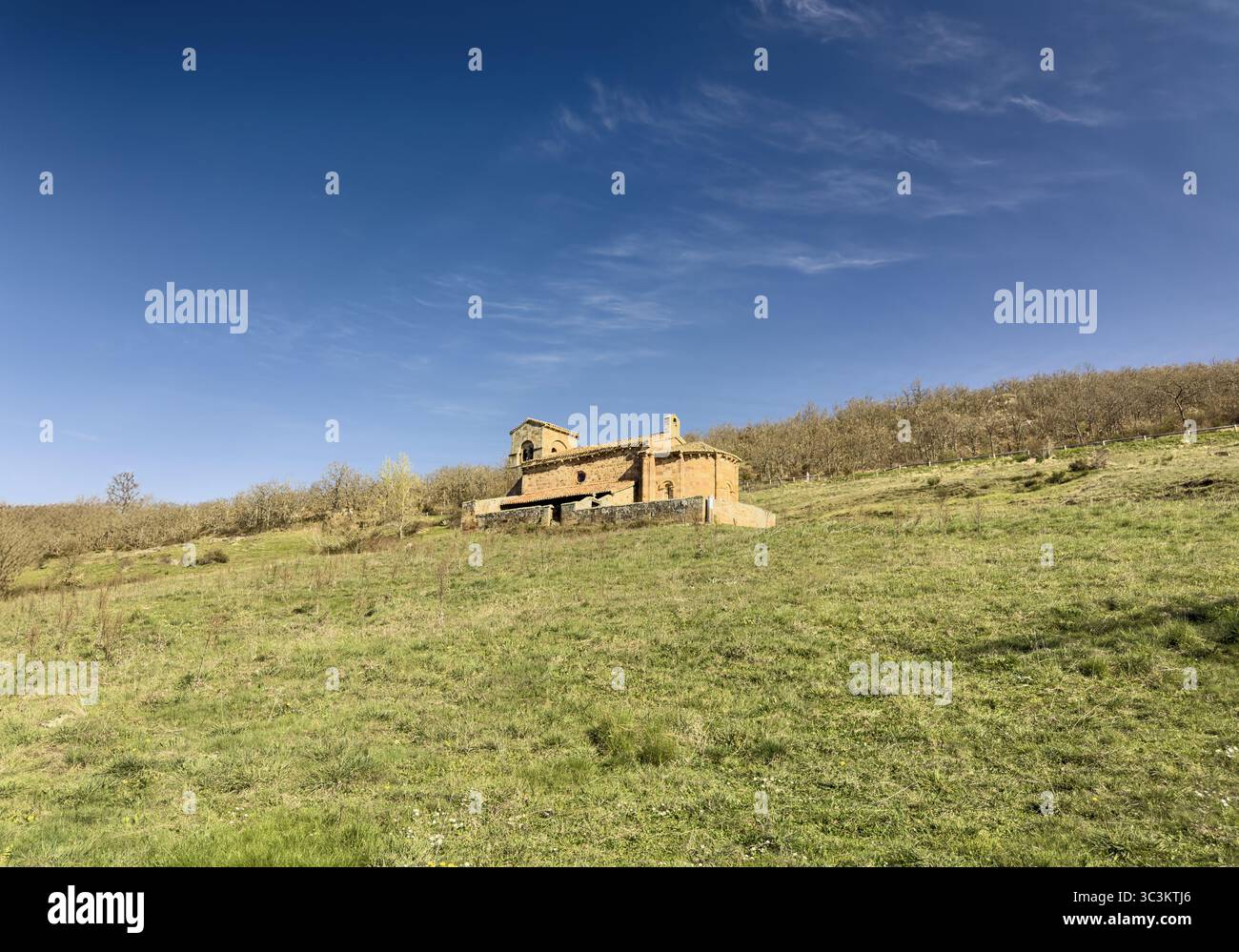 Storica chiesa romanica con pareti in pietra, tetto in piastrelle rosse e campanile annidato nella campagna di Palencia. Foto Stock