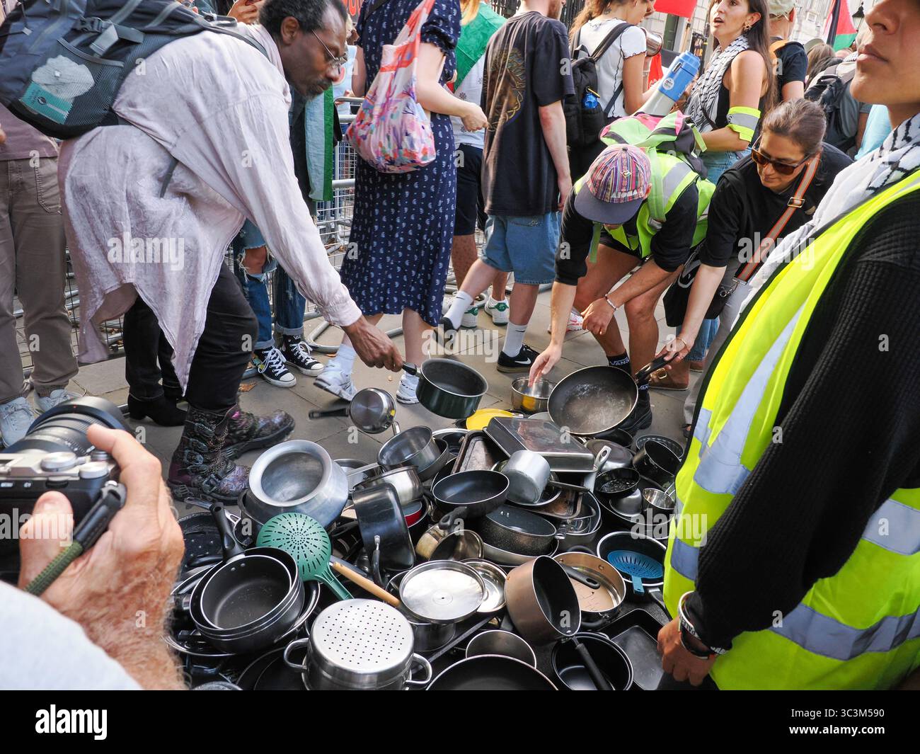 Regno Unito, Londra, Downing Street, 25 luglio 2025. Migliaia di persone si radunano fuori dall'ingresso di Downing Street e dalla residenza del primo ministro Keir Starmer che sbattono pentole e padelle e invitano il governo ad agire contro Israele per porre fine all'assedio e alla fame di Gaza. Le pentole e le padelle sono state poi disposte in righe ai lati dell'ingresso in un gesto simbolico per onorare la vita dei 1.000 palestinesi uccisi dall'IDF che tentavano di ottenere aiuti a Gaza. Crediti: Leo Bild/Alamy Live News Foto Stock