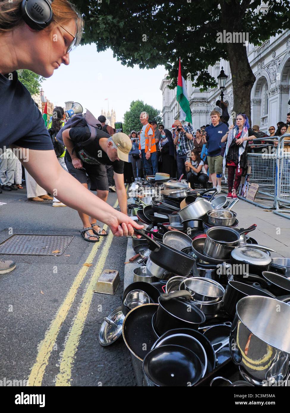 Regno Unito, Londra, Downing Street, 25 luglio 2025. Migliaia di persone si radunano fuori dall'ingresso di Downing Street e dalla residenza del primo ministro Keir Starmer che sbattono pentole e padelle e invitano il governo ad agire contro Israele per porre fine all'assedio e alla fame di Gaza. Le pentole e le padelle sono state poi disposte in righe ai lati dell'ingresso in un gesto simbolico per onorare la vita dei 1.000 palestinesi uccisi dall'IDF che tentavano di ottenere aiuti a Gaza. Crediti: Leo Bild/Alamy Live News Foto Stock