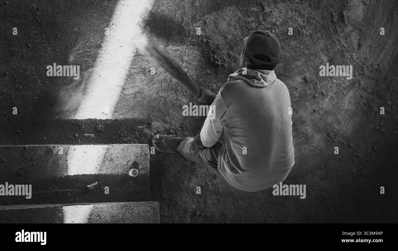 Una scopa attraversa il sito polveroso, sollevando in aria sabbia fine, catturando una disciplina tranquilla nel cuore di una zona di costruzione robusta. Foto Stock