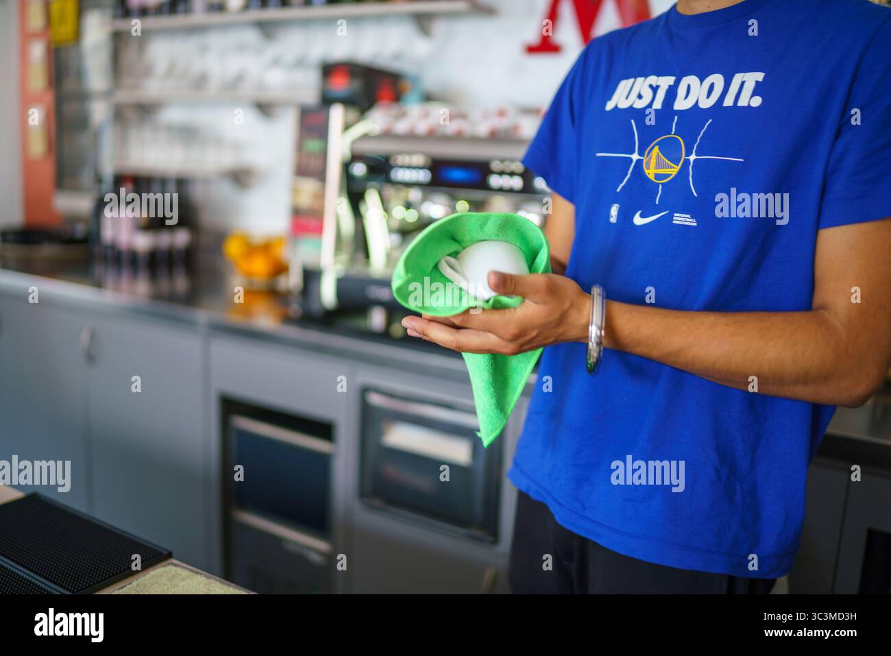 Cremona, Italia - 25 luglio 2025 macchina per il caffè Barista pulizia bacchetta a vapore con panno verde in microfibra per l'igiene e il servizio di qualità presso la caffetteria. Foto Stock