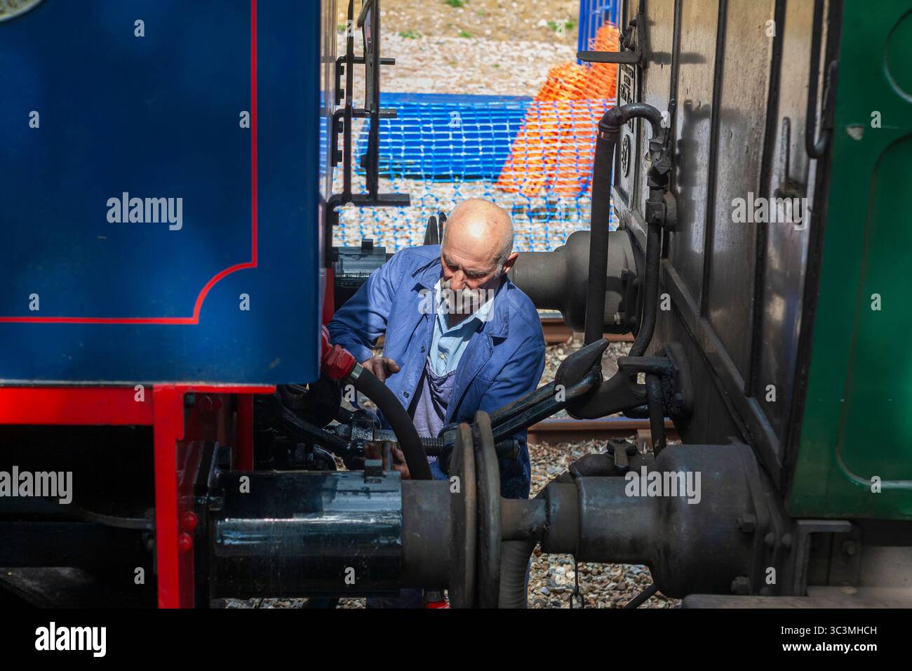 Accoppiamento di una locomotiva a vapore a un treno: Wootton Station sulla Isle of Wight Steam Railway, una ferrovia storica conservata sull'Isola di Wight, Regno Unito Foto Stock