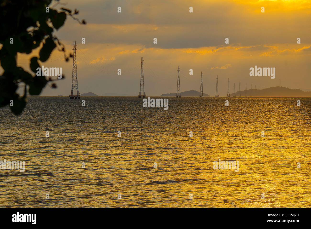 I poli elettrici del sistema di linee elettriche da ha Tien alle Isole Pirate si distinguono sulla superficie del mare nel brillante tramonto. Foto Stock