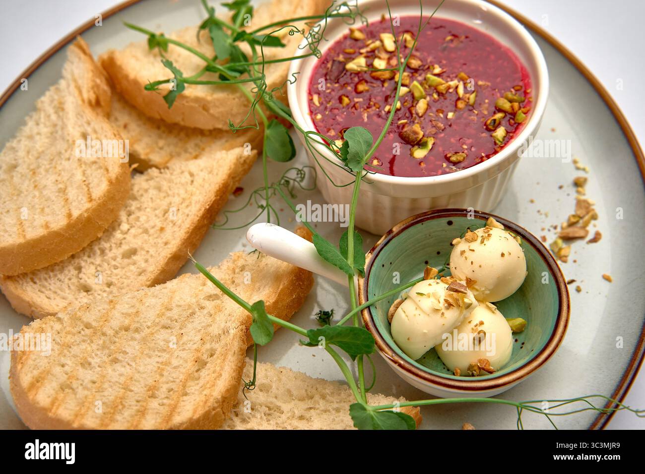 Un piatto deliziosamente presentato con pane salato, dessert cremoso e frutta secca spalmata con verdure fresche per un'esperienza culinaria soddisfacente Foto Stock