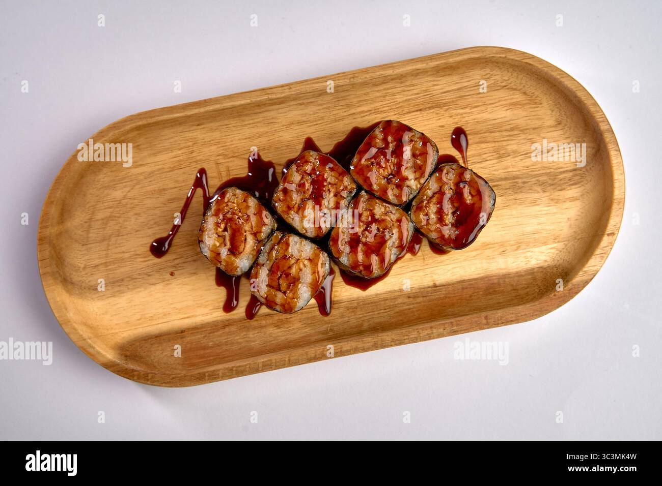 Sushi Rolls realizzati con gusto e conditi con salsa salata su un piatto di legno catturato in una bella presentazione Foto Stock