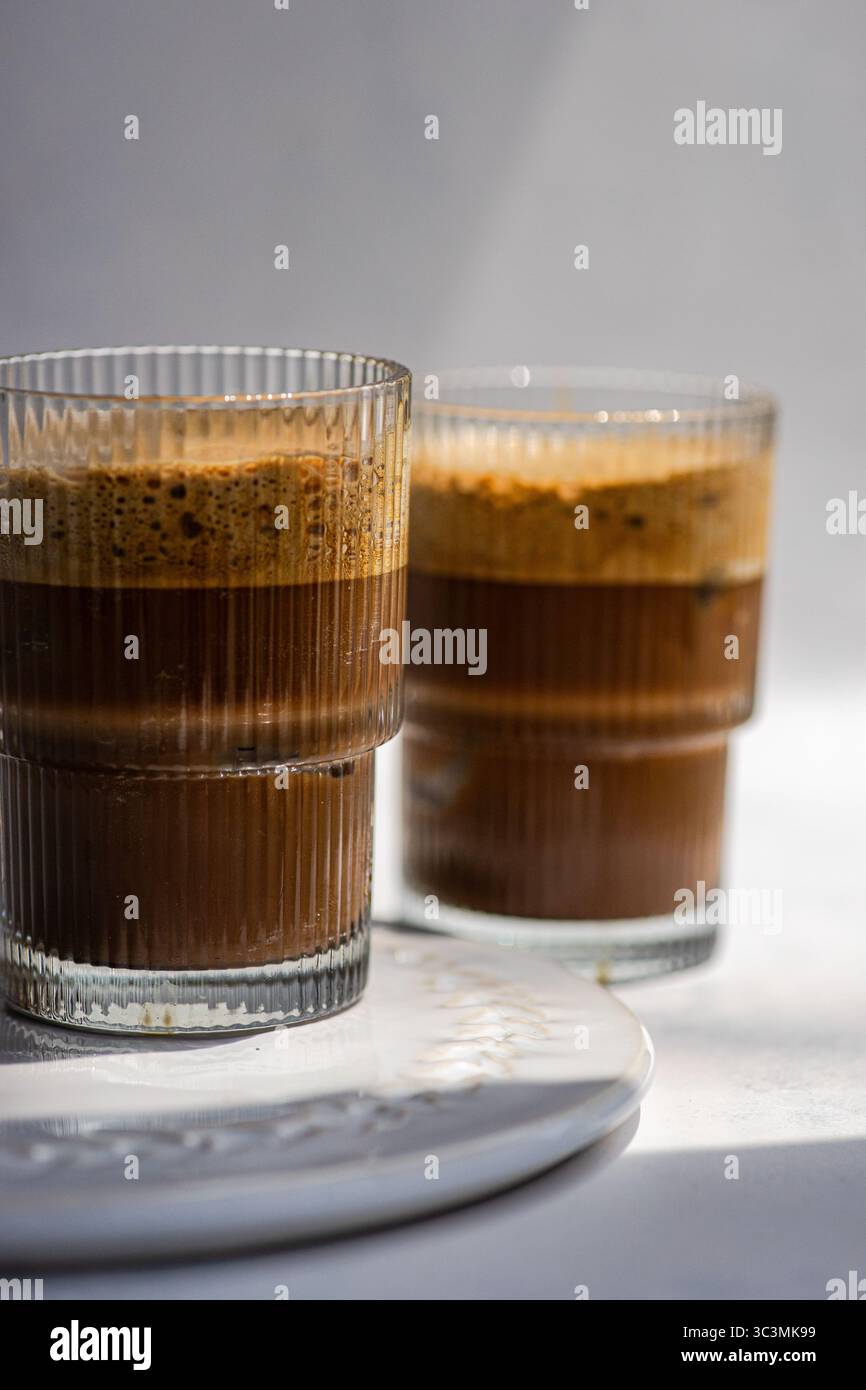 Due cappuccini freddi ghiacciati in eleganti bicchieri, con ricchi strati di espresso ricoperti di schiuma cremosa. Perfetto per una rinfrescante carica di caffeina Foto Stock