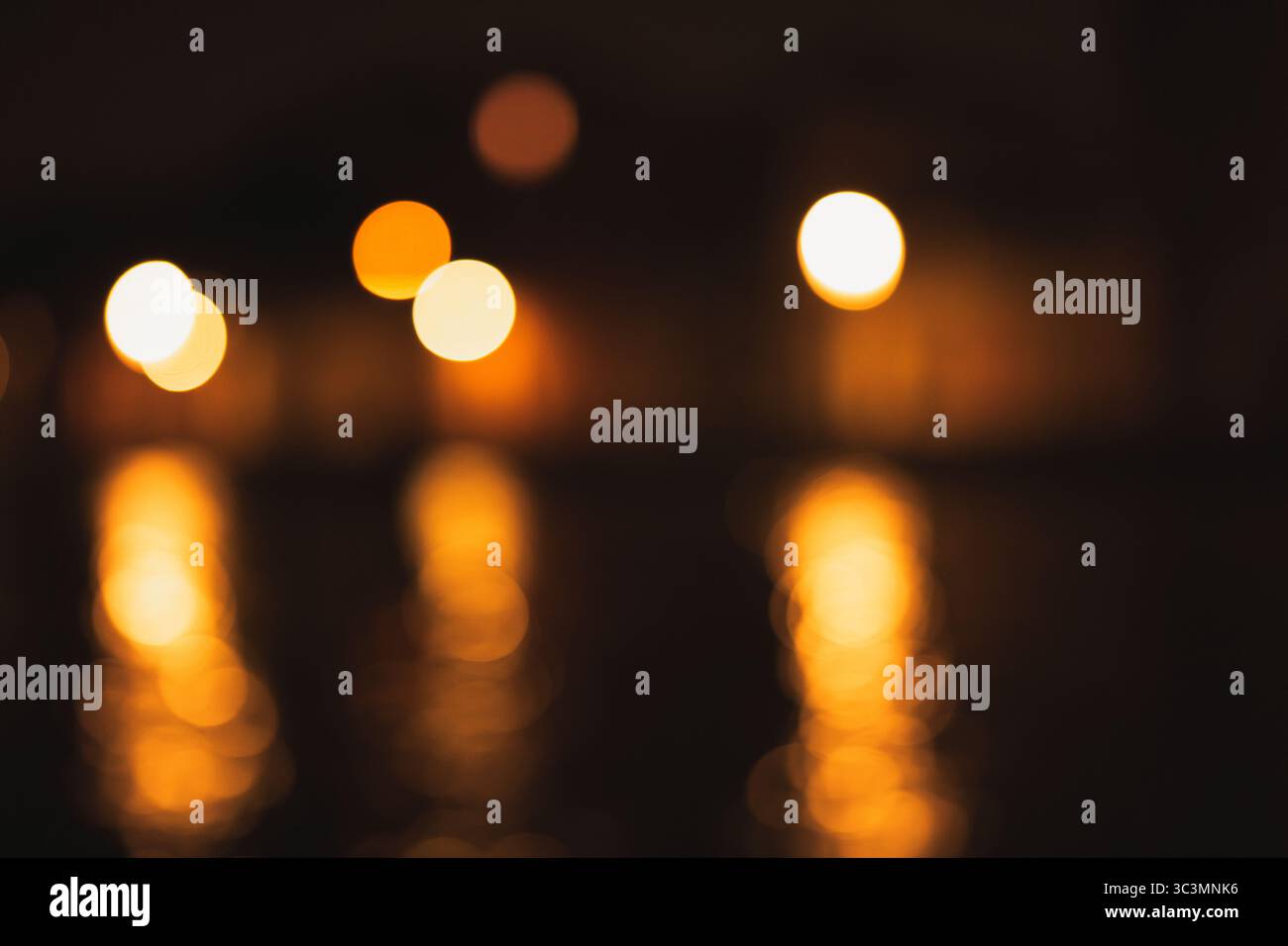 Un'affascinante immagine astratta di bokeh dorato che si riflette dolcemente su una superficie scura, creando un'atmosfera magica e serena con caldo e rilassante Foto Stock